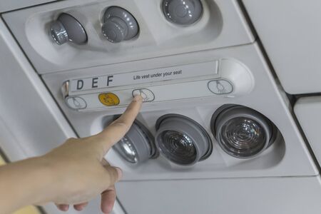 Passengers using the hand to turn on-off lights on the switch board on the plane.selective focus.の写真素材