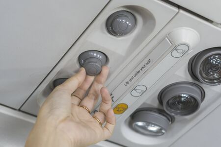 passenger adjusting air conditioning above seat while on board of an aircraft,selective focus.