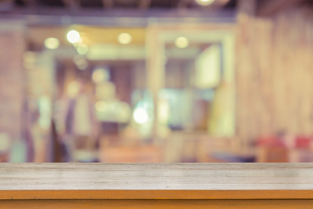 Empty brown wooden table and Coffee shop interior with some people meeting blur background with...