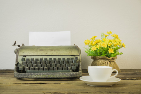 Old typewriter with blank paper,Old retro typewriter on table on white background,Retro typewriter placed on wooden,Vintage typewriter and a blank sheet of paper,vintage tone,selective focus on cup of coffee.の写真素材