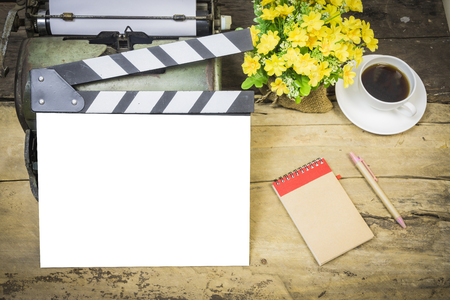 retro typewriter on table,vintage photo of movie clapper on wood,flower pot blank note book and a cup of coffee,film or short film concept,vintage tone,selective focus.の写真素材