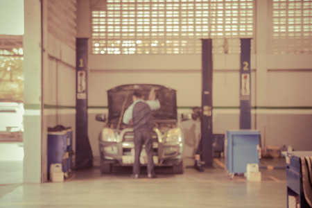 Blurred of car technician repairing the car in garage background, Interior of a car repair station,Cars servicing at Service station,car mechanic work at repair service station garage,vintage color.の写真素材