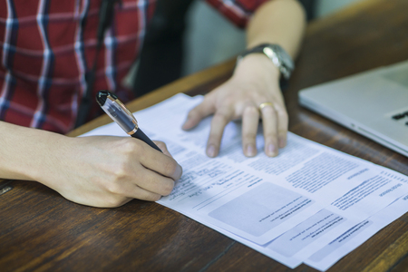Close-up Of Businessperson Signing Contract,Man writing paper at the desk, man writing with pen and reading books at table,man Signing, Contract, Form. in office ,morning light ,selective focus.?の写真素材