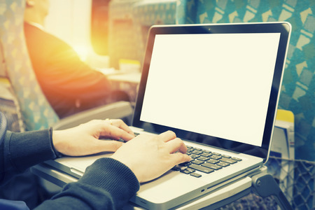 Close-up woman hands typing on a laptop keyboard in the train,sitting next to the window and looking at computer screen. Concepts of travel and lifestyle.,selective focus,vintage colorの写真素材