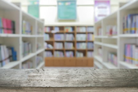 Empty brown wooden table and blur background of library setting with books and reading material ,can be used for montage or display your productsの写真素材