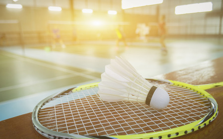 A set of badminton concept.Badminton ball (shuttlecock) and racket on court floor,Paddle and the shuttlecock and badminton courts with players competing in modern gym,selective focus,vintage colorの写真素材