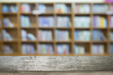 Empty brown wooden table and blur background of library setting with books and reading material ,can be used for montage or display your productsの写真素材