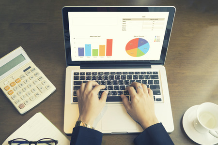 business woman use online laptop computer for analyzing financial chart,writing business plan,open net-book,phone,tablets,with copy space screen,morning light,vintage colorの写真素材