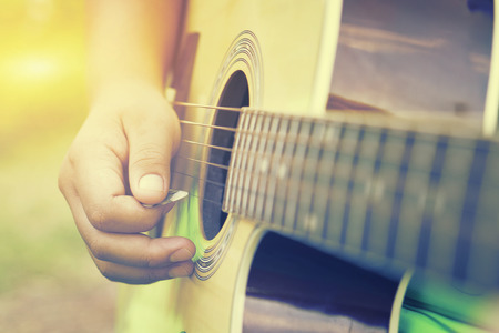 Relaxing Musical concept,Practicing in playing guitar. Handsome young men playing guitar,man's hands playing acoustic guitar, close up,selective focus,vintage colorの写真素材