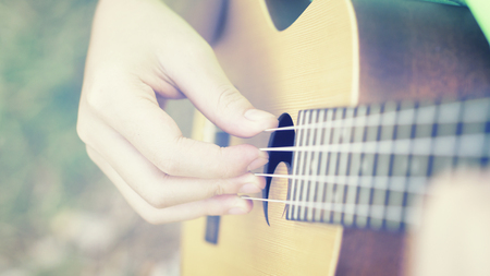 woman handicraft playing ukulele. Hands playing a musical instrument.relaxing and free people on Ukulele (mini guitar) at the park,sunset vintage tone,selective focus,copy space for advisingの写真素材