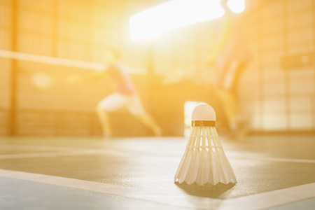 A set of badminton concept.Badminton ball (shuttlecock) and racket on court floor,Paddle ,the shuttlecock and badminton courts with players competing in modern gym,selective focus,vintage colorの写真素材