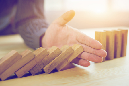 Problem Solving,Hand Stopping Domino Effect,businessman stop effect of dominoes continuous toppled with hand at desk,retro style image executive and risk control concept,selective focus,vintage colorの写真素材