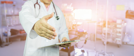 Handshake Gesture from Doctor with stethoscope on operating room,doctor writing patient record after examine health. success medical working in hospital,selective focus. healhcare and medical conceptの写真素材