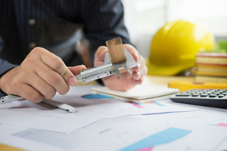 architect work concept.man working with new startup project in modern loft. Drawning pen,inspection engineer report with product and vernier calipers,engineer architectural project,Notebook on tableの写真素材