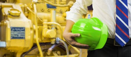engineering management construction helmet,engineer or worker hold in hand yellow helmet for workers security  on working  site background.  business Man ,management ,selective focus,vintage toneの写真素材