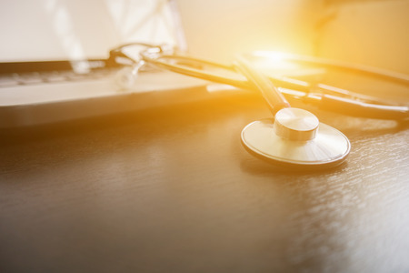 Stethoscope on laptop keyboard,stethoscope on the keyboard of pc,Medical Stethoscope Resting on Desk,relax time doctor,selective focus,vintage color.morning lightの写真素材