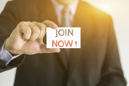 Man's hand holding card with JOIN NOW messageの写真素材