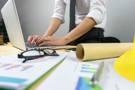 architect man working with laptop and blueprints,engineer inspection in workplace for architectural plan,sketching a construction project ,selective focus,Business concept vintage colorの写真素材