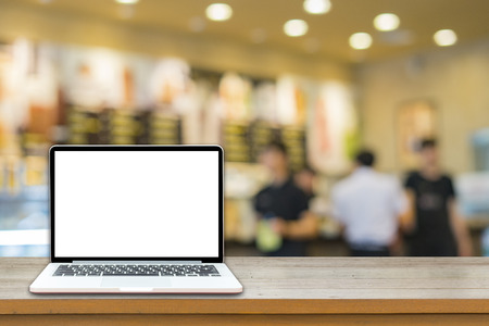 Open laptop computer  lying on a wooden table in cafe bar interior, portable net-book with copy space screen for your information content or text message, freelance ,internet,vintage colorの写真素材
