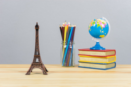 Eiffel tower statue and stack of book ,color pencil and globe on the school desk,knowledge school...