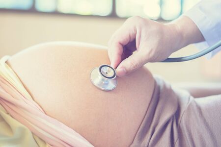 doctor using stethoscope white examining pregnant woman in clinic,Medical exam new born concept,vintage color selective focusの写真素材