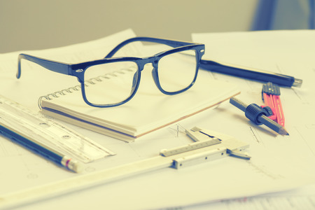 glasses on office desk and office supplies.office desk table with a lot of things on it.and business people meeting and writing business plan in background,copy space.vintage color.selective focus.の写真素材