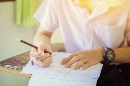 Student hand holding pencil writing doing examination with blurred abstract background university...