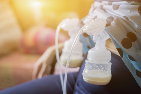 Automatic breast pump, mothers breasts milk is the most healthy food for newborn baby. Happy mother with babys at bed room ,home,vintage color,copy spaceの写真素材