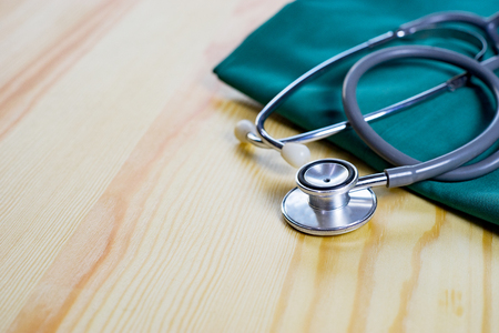 Stethoscope and medical equipment with doctor coat on wooden table shallow DOF evenly matched and background,Resting on Desk,relax time ,selective focus,vintage colorの写真素材