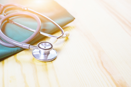 Stethoscope and medical equipment with doctor coat on wooden table shallow DOF evenly matched and background,Resting on Desk,relax time ,selective focus,vintage colorの写真素材