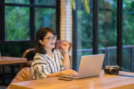 Asian woman working in co-working space project with generic design laptop. Analysis plans hands,Girl smiling and looking at digital screen,she checking email,mailbox about her payment online shoppingの写真素材