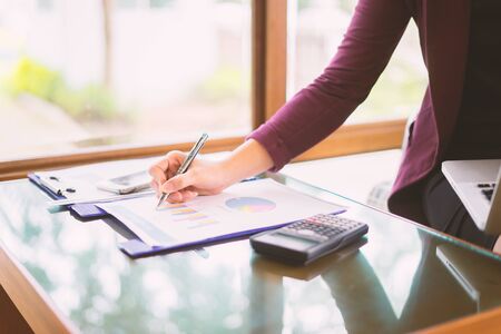 Hand business woman pointing paper data analyze chart on desk at office room.young girl writing into her diary about recipient address on mailing envelope,female hands sending letter,business conceptの写真素材