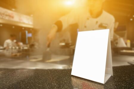 Mock up Label the blank menu frame in Bar restaurant ,Stand for booklets with white sheets paper acrylic tent card on wooden table cafeteria blurred background can inserting the text of the customer.の写真素材
