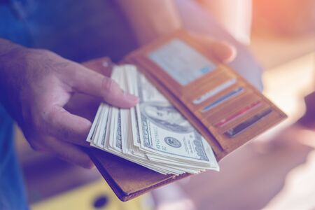 man's hands taking out money from a violet leather wallet.の写真素材