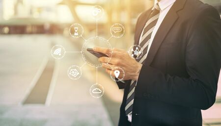 Internet of Things(IOT) concept with young man holding his smartphone  by hand with mobile network communication technology, diagram showing many connected devices icons.の写真素材