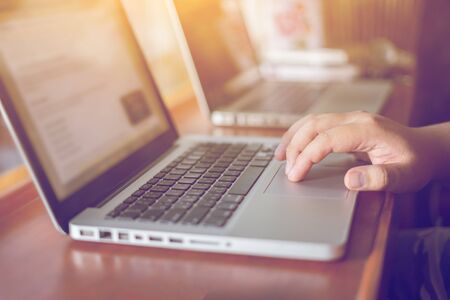 Hand on touchpad of laptop in back light on notebook with his finger, toned with sunlight using,gadgets recreation time in coffee shop,vintage color,selective focus.の写真素材