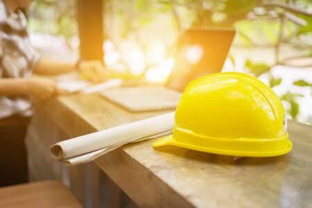 yellow hard safety helmet hat for safety project of workman as engineer  on work place, architect man working with laptop on background,construction project ,Business conceptの写真素材