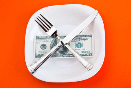 dollar on plate with fork and knifeの写真素材
