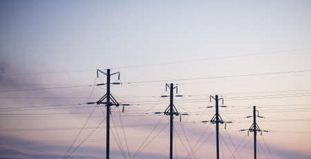 Electricity pylons and lines above a freeway  at sunriseの写真素材