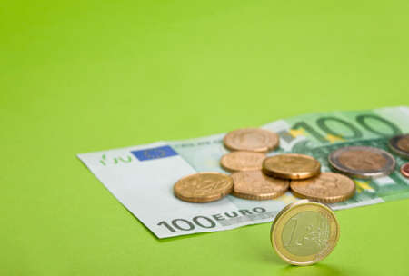 One hundred Euro bill and coins on the paperの写真素材