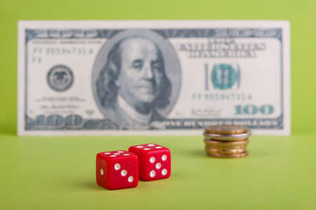 Two  dices in front of dollar  banknote and coinsの写真素材