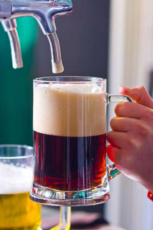 glass being filled with draft beer by barmanの写真素材