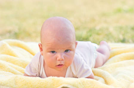 Cute baby boy lying on her belly in a yellow towelの写真素材