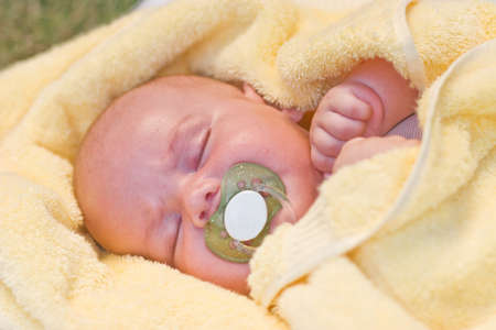 baby sleeping in a yellow towel in nature with nipple