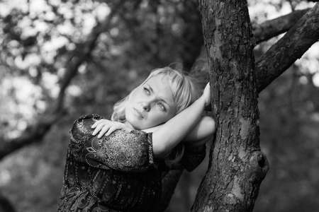 Beautiful Sadness girl sitting on a tree branchの写真素材