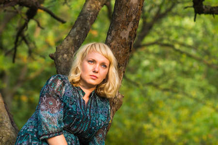 Beautiful Sadness girl sitting on a tree branchの写真素材