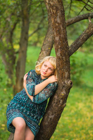 Beautiful Sadness girl sitting on a tree branchの写真素材