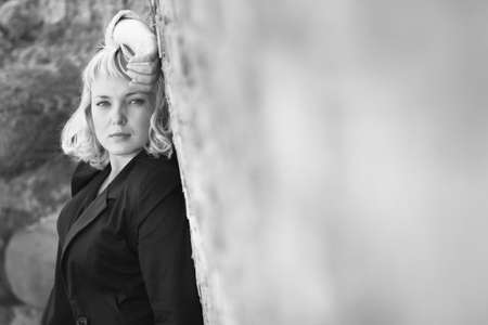 Beautiful  blonde caucasian young woman standing near the wall and looks into the cameraの写真素材