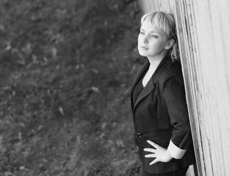 Beautiful  blonde caucasian young woman standing near the wall and looks into the distanceの写真素材