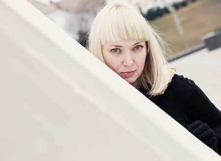 Beautiful  blonde caucasian woman standing near the wall and looks into the cameraの写真素材